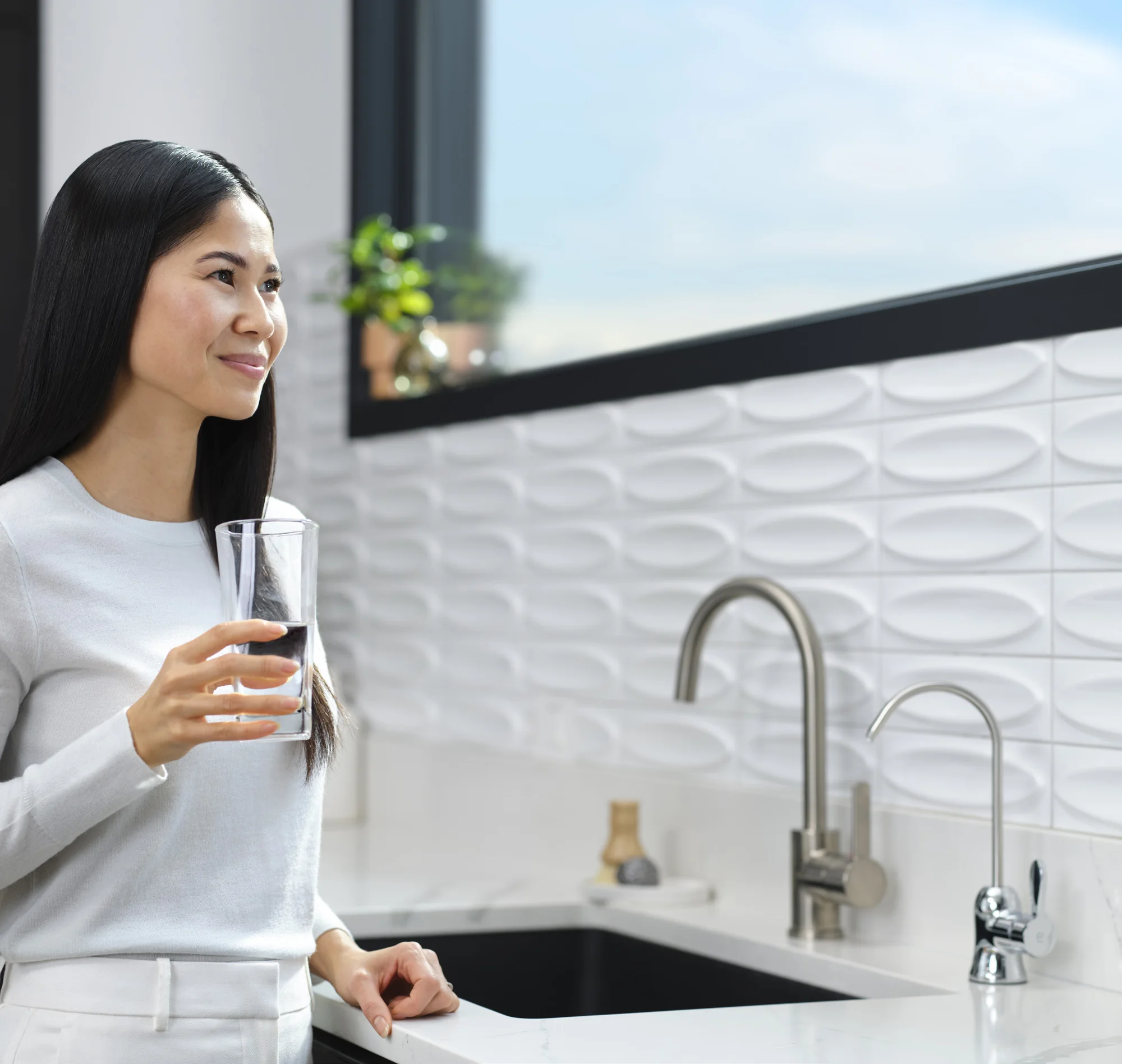 Mujer bebiendo un vaso de agua junto a la ventana