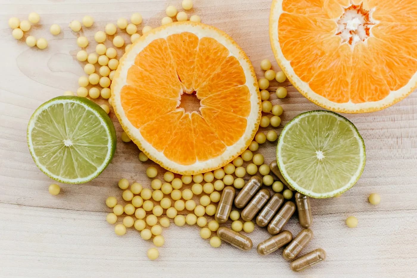 Cápsulas de suplemento junto a naranjas y limas cortadas